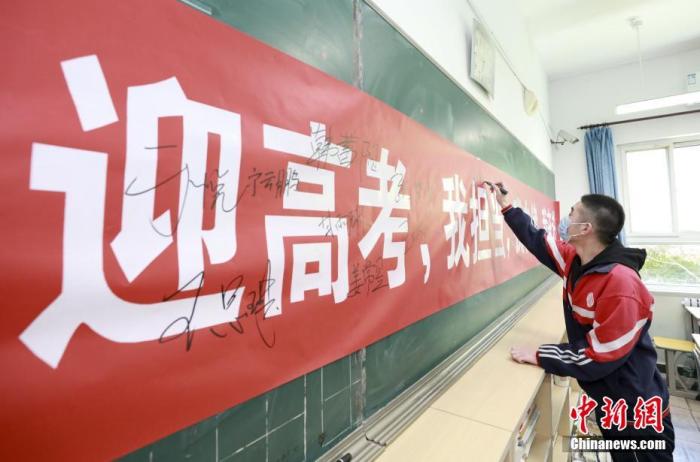 资料图:4月23日,在河北省廊坊市大厂回族自治县回民中学,学生在迎战高考的主题条幅上签名。<a target='_blank' href='http://www.chinanews.com/'>中新社</a>记者 宋敏涛 摄 点击进入下一页