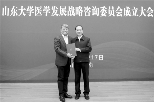 山东大学党委书记郭新立,向受聘的医学发展战略咨询委员会主任委员韩启德(右)颁发聘书。 记者王晓峰摄