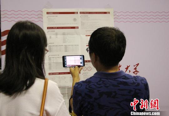 考生和家长在现场用手机拍摄高校录取情况信息。　赵晓 摄