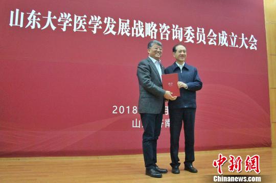 山东大学党委书记郭新立向十二届全国政协原副主席、医学发展战略咨询委员会主任委员韩启德颁发聘书。　赵晓 摄