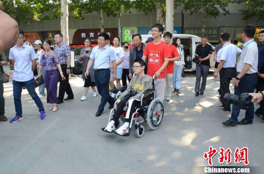 山东大学物理学院的学生主动从张玉坤手中接过轮椅，照顾张连川。　孙婷婷 摄